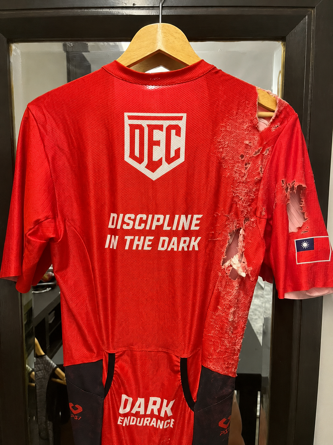 Marcus's torn trisuit after the crash — the kit took the damage, the flag stayed intact